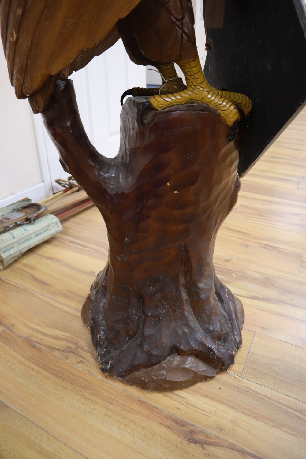 A carved and painted wood model of a Bald Eagle perched on a tree stump and a carved and painted wood hanging sign